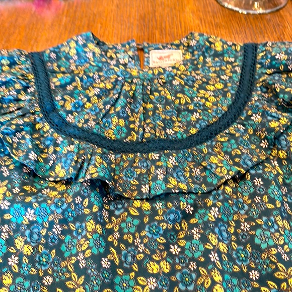 Colorful women’s blouse with inset detail, ruffle and biotin closure.